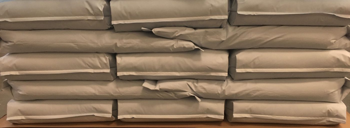 Picture of some beige bags that are filled with product and stacked onto a pallet.